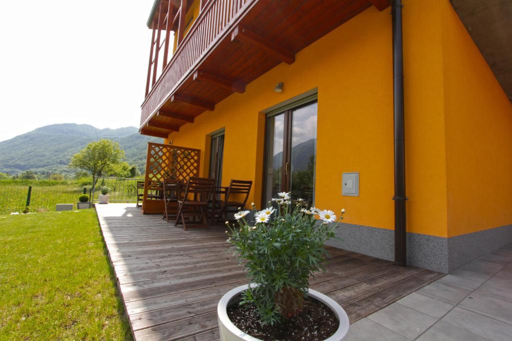 a porch of a yellow house with a table and chairs at Apartments Maligoj in Tolmin