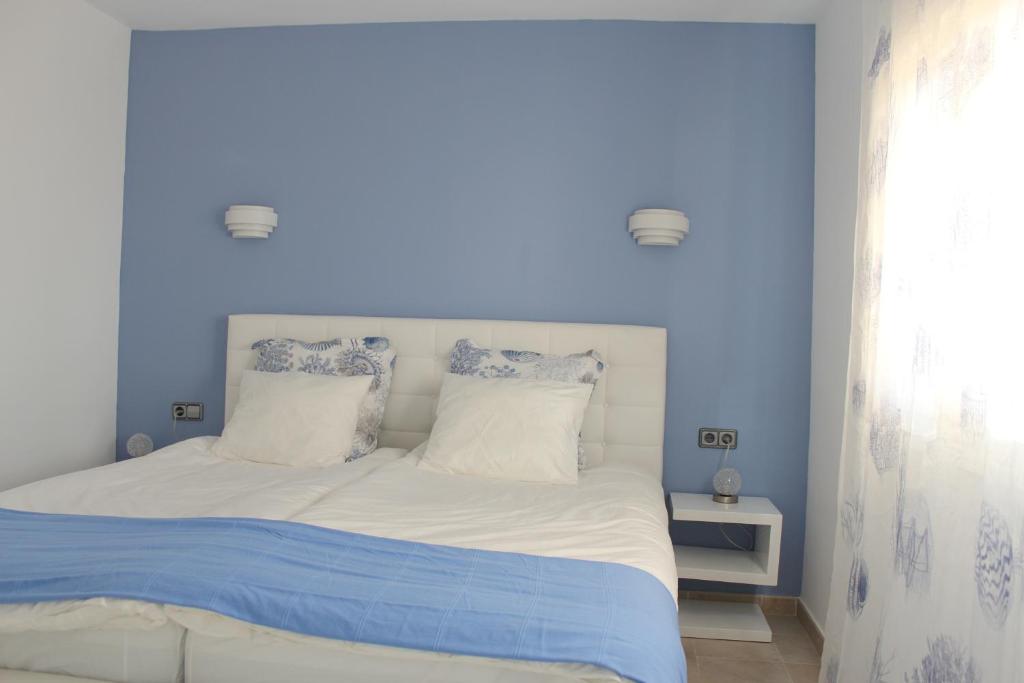 una camera blu con un letto con lenzuola e cuscini bianchi di Canyamel Beach a Canyamel