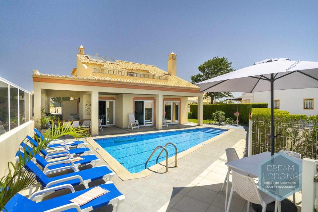 uma villa com uma piscina, cadeiras e um guarda-sol em Villa Rafaella 3 Dream Lodging em Albufeira