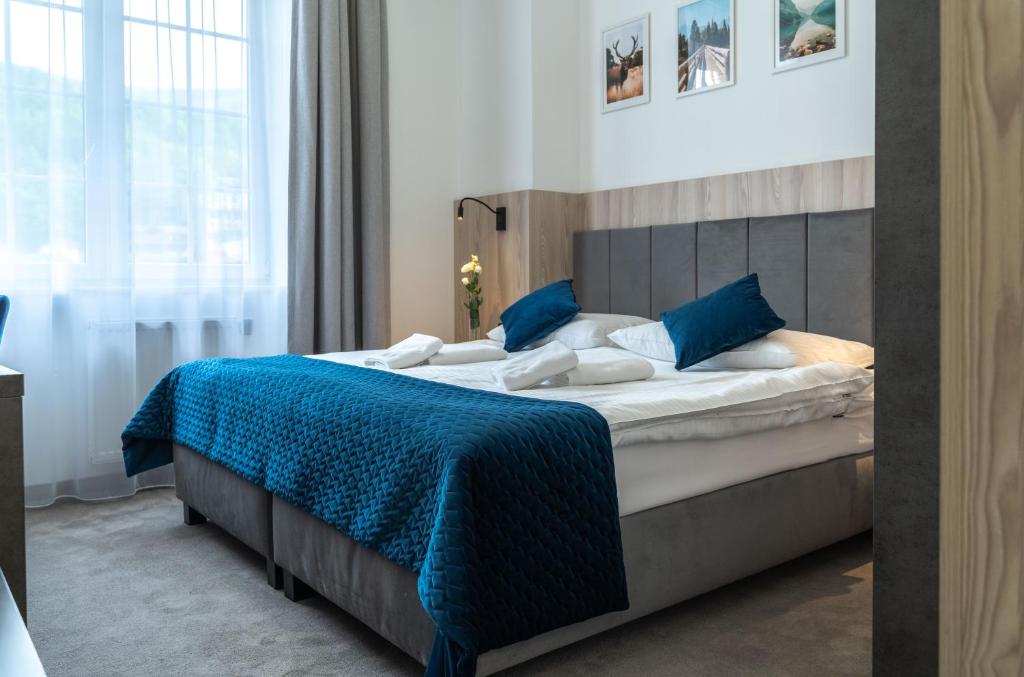 a bedroom with a large bed with a blue blanket at Hotel Alpin in Szczyrk