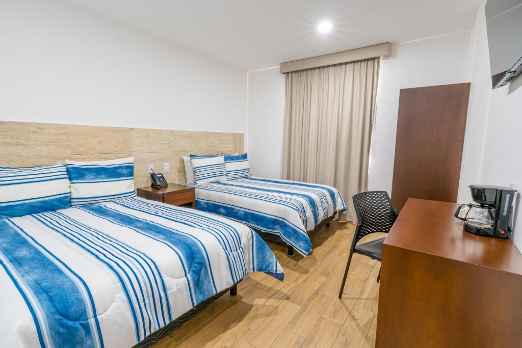 Hotel Pacific Blue Mazatlan في مازاتلان: غرفة فندقية بسريرين ومكتب