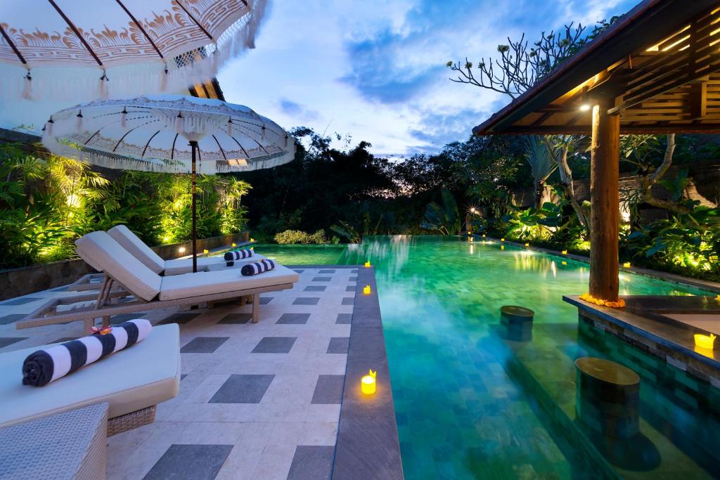 a pool at a resort with a lounge chair and an umbrella at Adepa Resort in Canggu