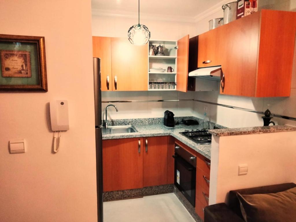 uma cozinha com armários de madeira, um lavatório e um frigorífico em Marina Golf Asilah em Asilah
