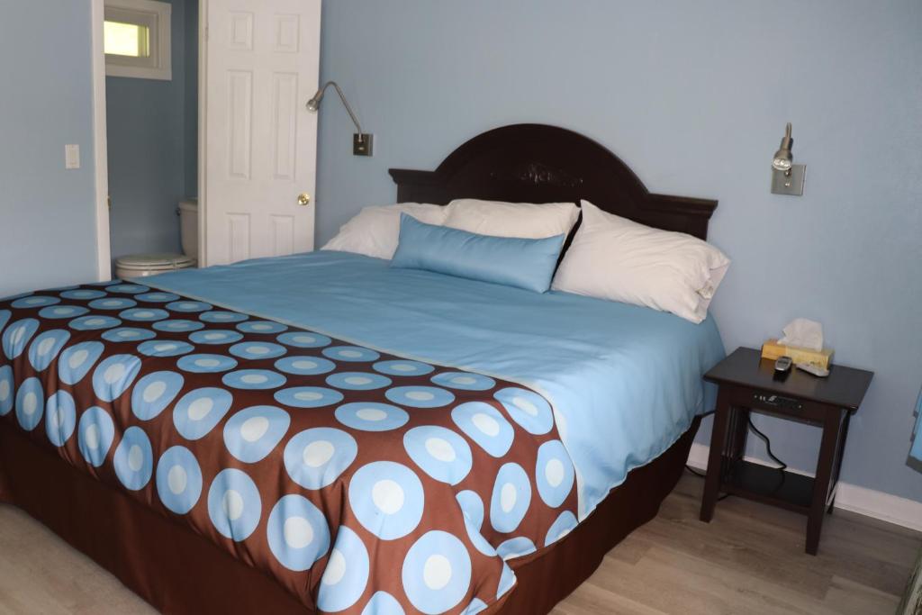 ein Schlafzimmer mit einem großen Bett mit einer blauen und weißen Bettdecke in der Unterkunft Hitching Post Motel 