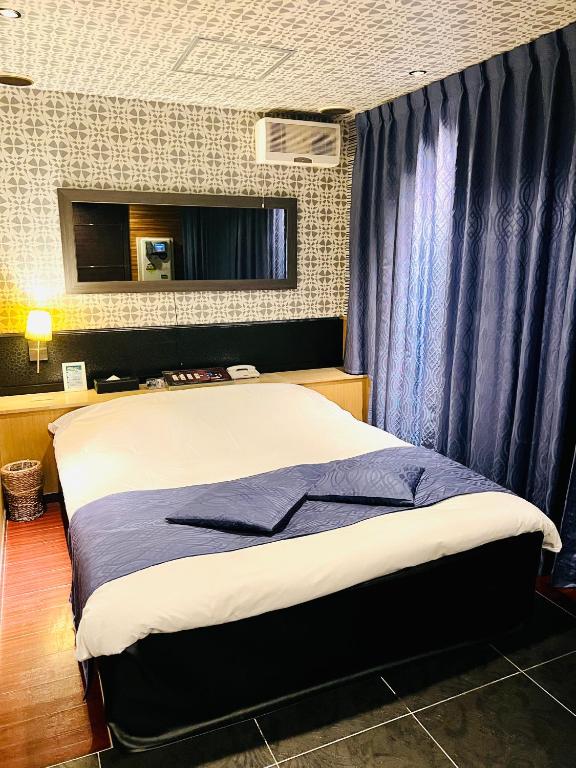 um quarto com uma cama grande e cortinas azuis em ホテル CROWN MOTEL em Yokohama