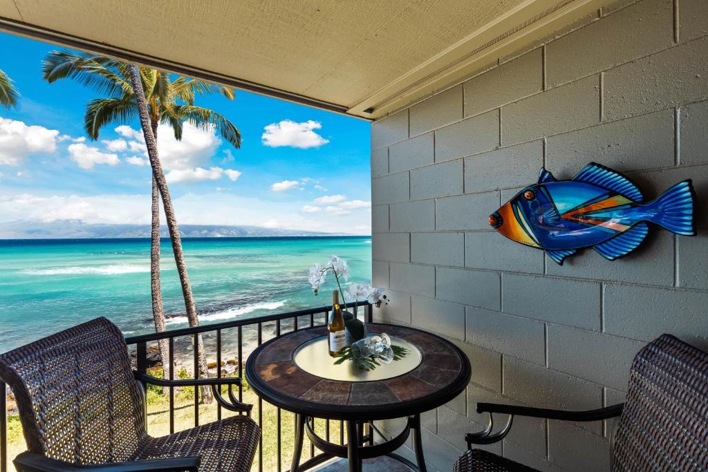 a balcony with a table and chairs and the ocean at Noelani 208 in Kahana