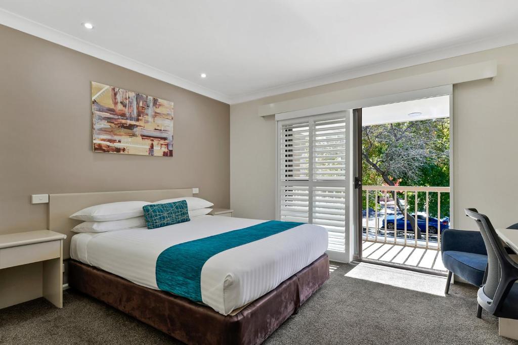 a bedroom with a bed and a desk and a window at Central Caleula Motor Lodge in Orange