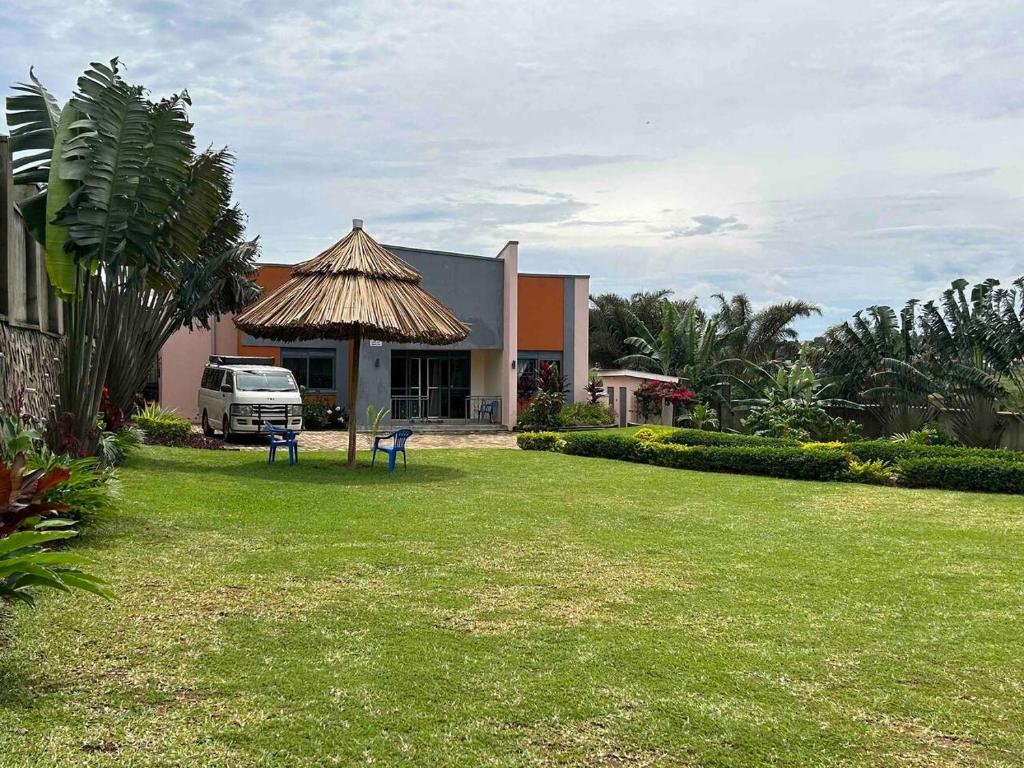 a house with a grass yard with a van in front of it at Amazing lake Victoria Villa, Entebbe in Entebbe