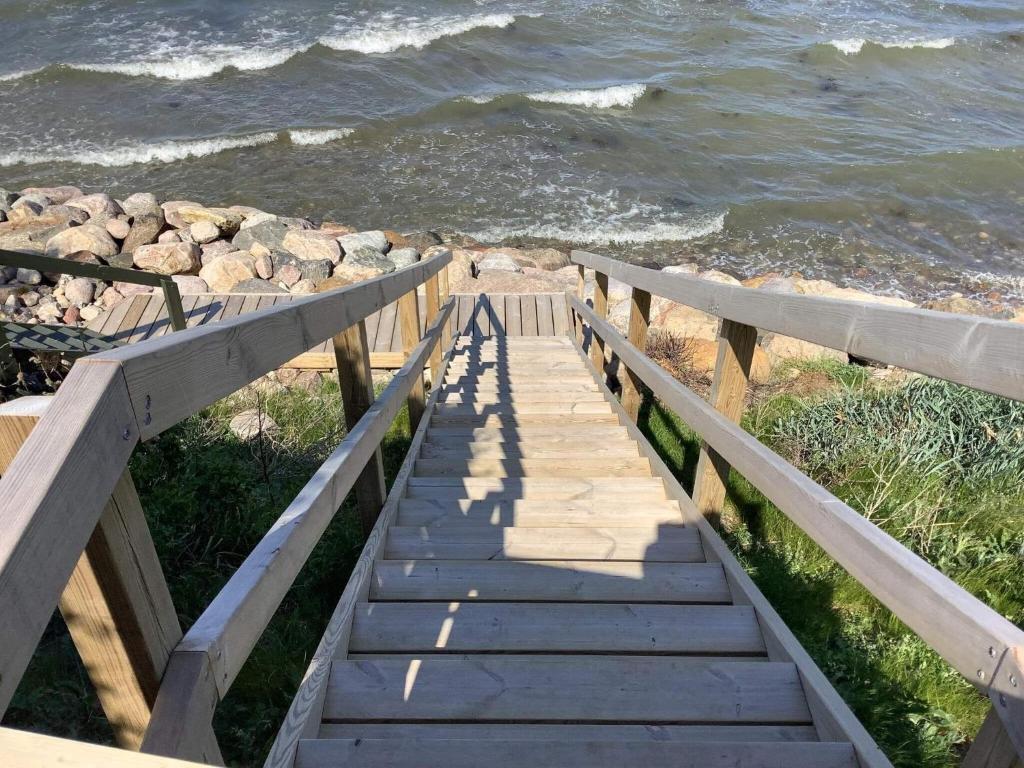 a staircase leading down to the beach with the ocean at Holiday home Jægerspris XVII in Jægerspris