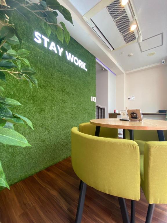 an office with a green wall with a table and yellow chairs at ステイワーク錦糸町 in Tokyo