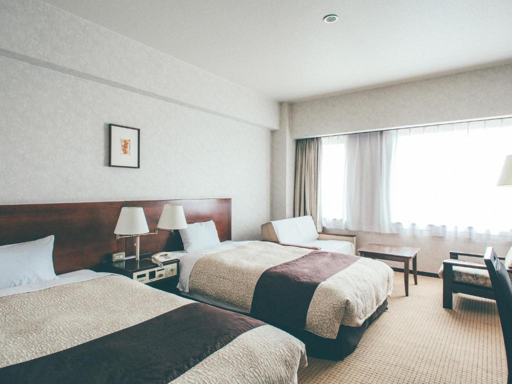 Postel nebo postele na pokoji v ubytování Kanazawa Kokusai Hotel