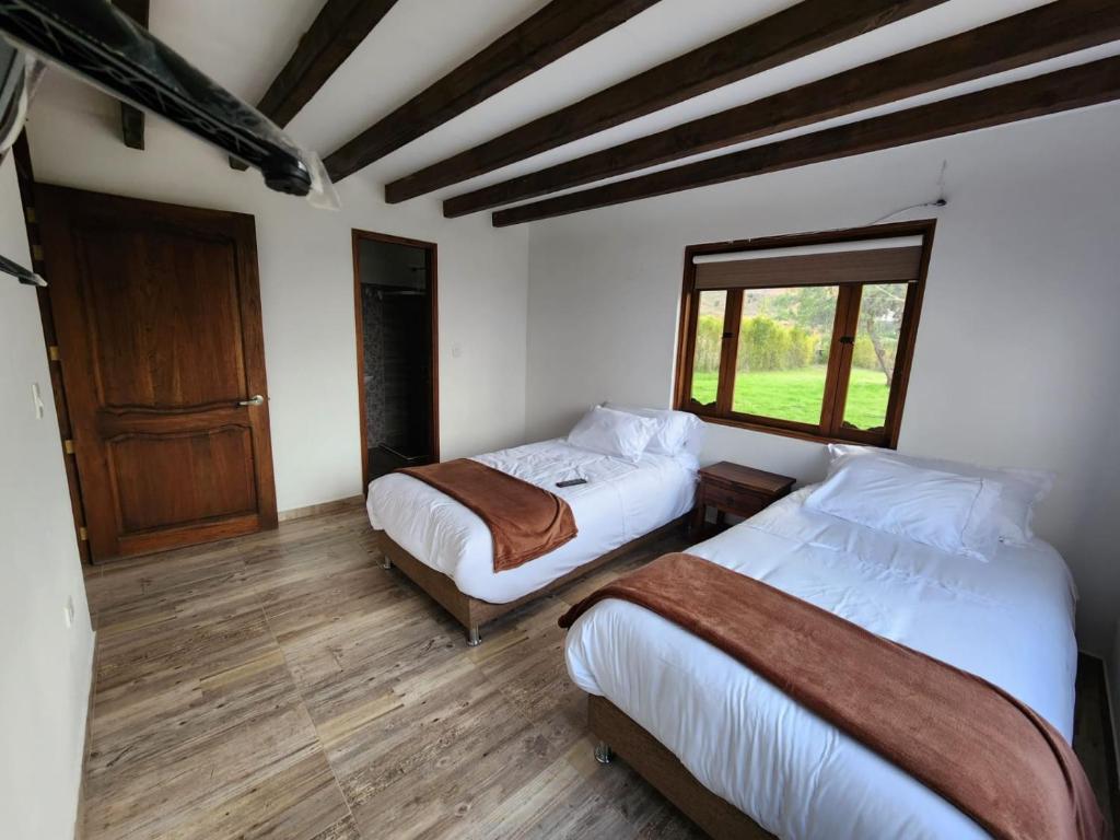 a bedroom with two beds and a window at Cabaña San Talis in Sáchica