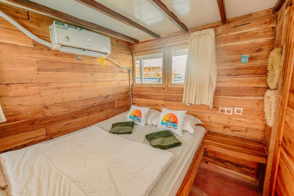 a small bedroom with a bed in a wooden cabin at Boat Open Trip Komodo 3Days 2 Nigths in Labuan Bajo