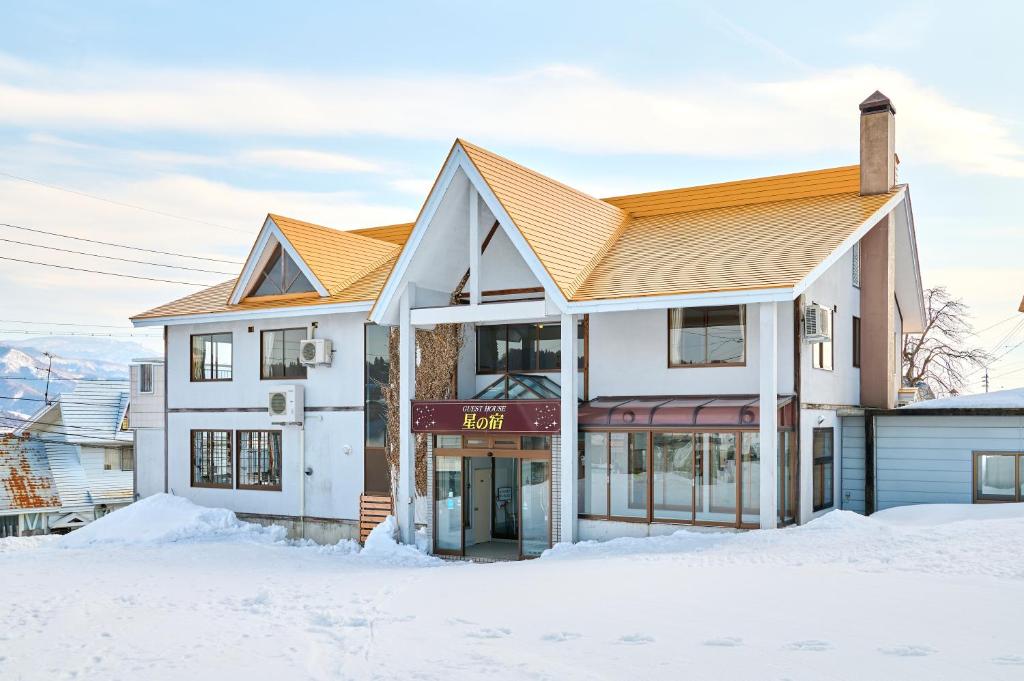 a white house with an orange roof in the snow at 星の宿　Hoshi no Yado in Iiyama