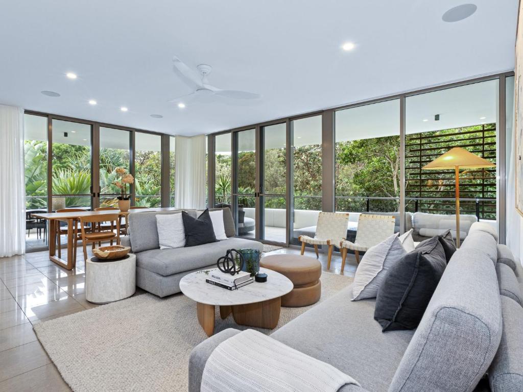 a living room with couches and tables and windows at Cotton Beach 94 Mid-Floor Penthouse with Bush View in Casuarina