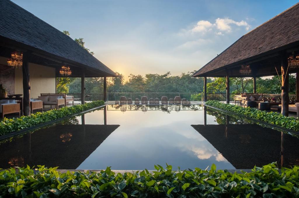 a pool at a resort with chairs and tables at Komaneka at Bisma Ubud in Ubud