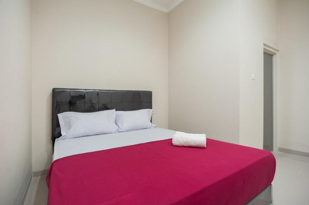um quarto com uma cama grande e um cobertor rosa em Hanna Residence near RSPI Puri Indah Mitra RedDoorz em Meruya-hilir