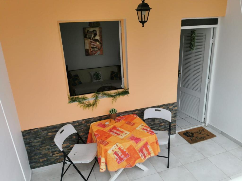 a dining room with a table and chairs and a mirror at Abri Papaye in Rivière-Salée