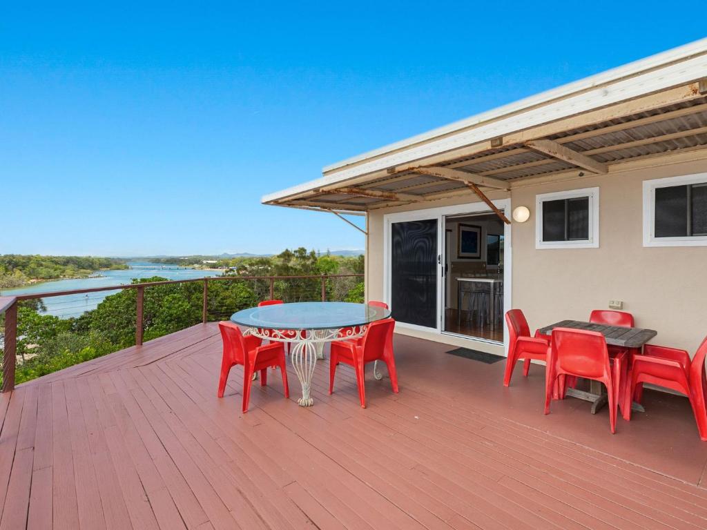 a patio with red chairs and a table on a deck at The Point - Panoramic Views over Pottsville Creek in Pottsville