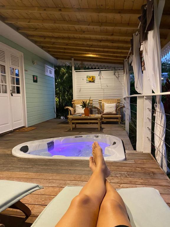 eine Frau, die vor einer Whirlpool-Badewanne liegt in der Unterkunft Villa Gaïa - Bungalow Ti-Zen et son jacuzzi niché dans un jardin tropical, séjour en amoureux in Le Diamant