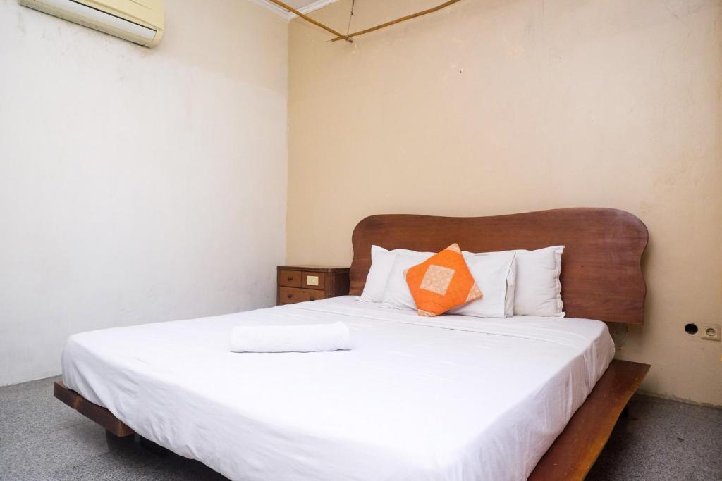 Dormitorio con cama con almohada naranja en My Cafe Hotel near UGM Yogyakarta Mitra RedDoorz, en Kejayan