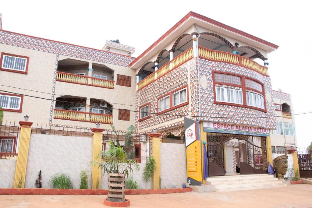 a large building with a yellow sign in front of it at Alafia Hotel Ketou in Kétou