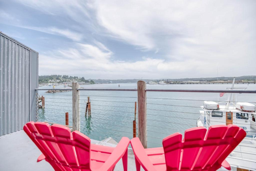 2 sillas rojas sentadas en un balcón con vistas a un cuerpo de agua en Ocean's Edge - Anchor Pier Lodge en Newport