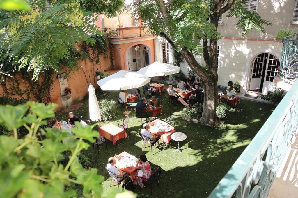 a group of people sitting at tables in a garden at Hôtel du Fiacre in Carpentras
