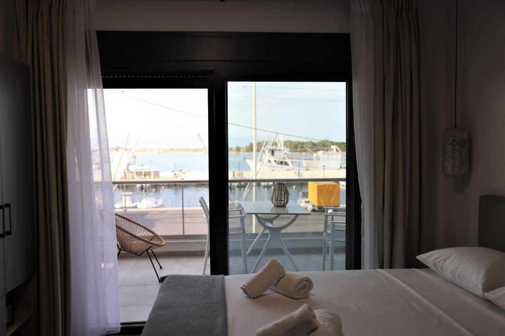 a bedroom with a bed and a balcony with a view at Nautico Rooms in Keramotí