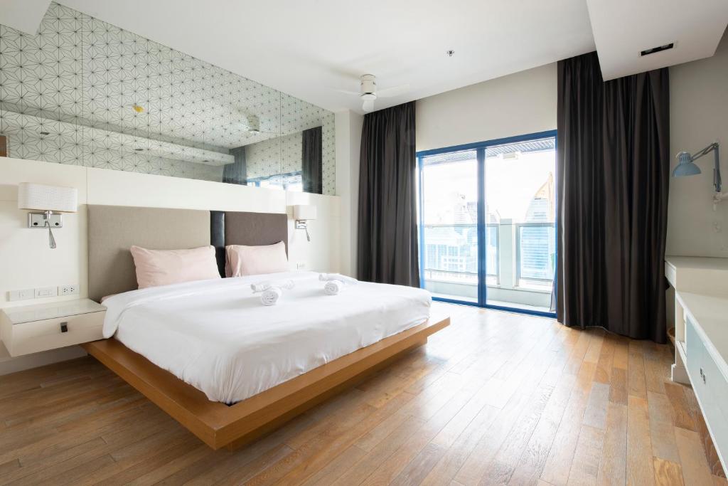 een slaapkamer met een groot bed en een groot raam bij M Estate 2BR Private Residence, 300m to BTS Chit Lom in Bangkok