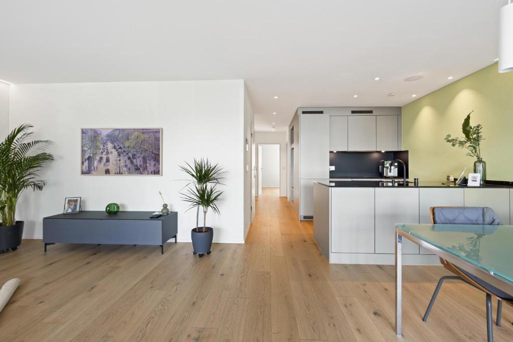 a kitchen and living room with white cabinets and a table at The R Apartment Uetliberg, Klima, Parken - Wallbox in Geroldswil