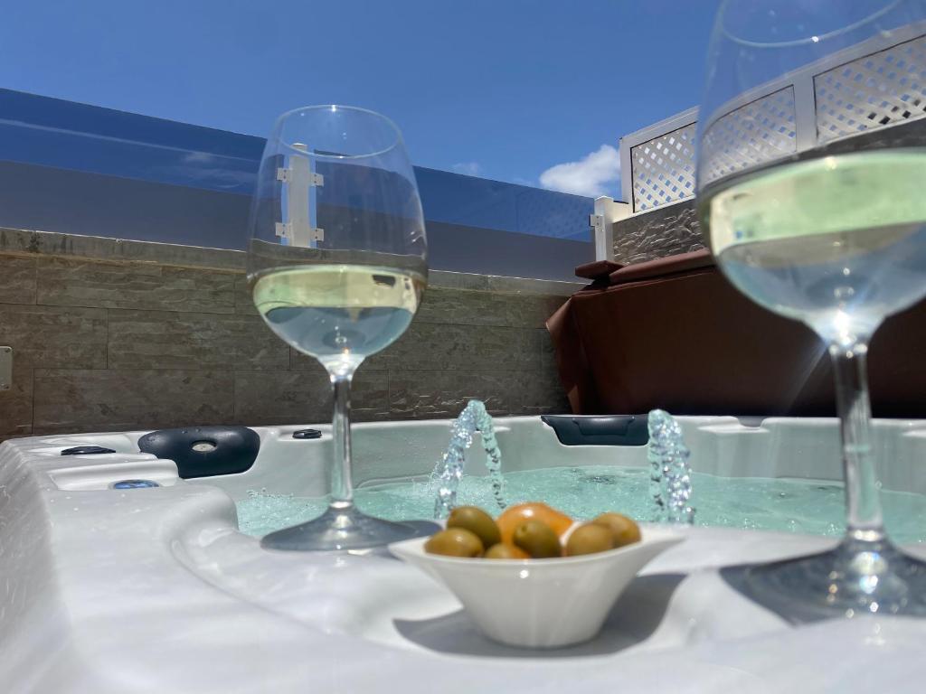dos copas de vino y un tazón de tomates en una bañera en Apartment With Jacuzzi and pool access en Puerto Rico