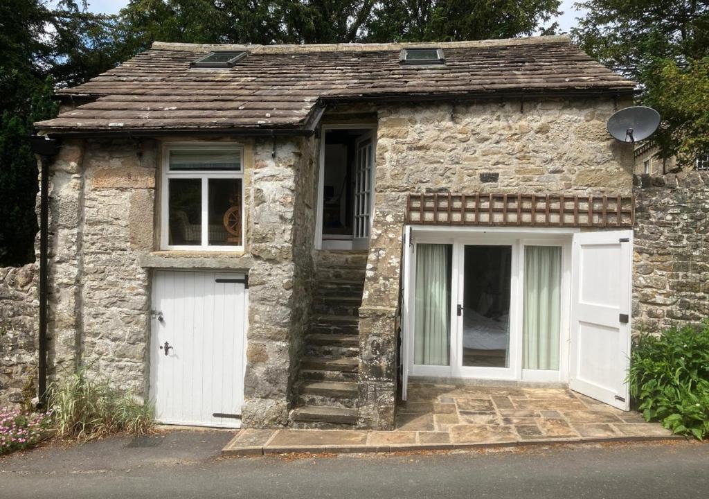 a small stone house with a white garage at Mullions Nook in Buckden