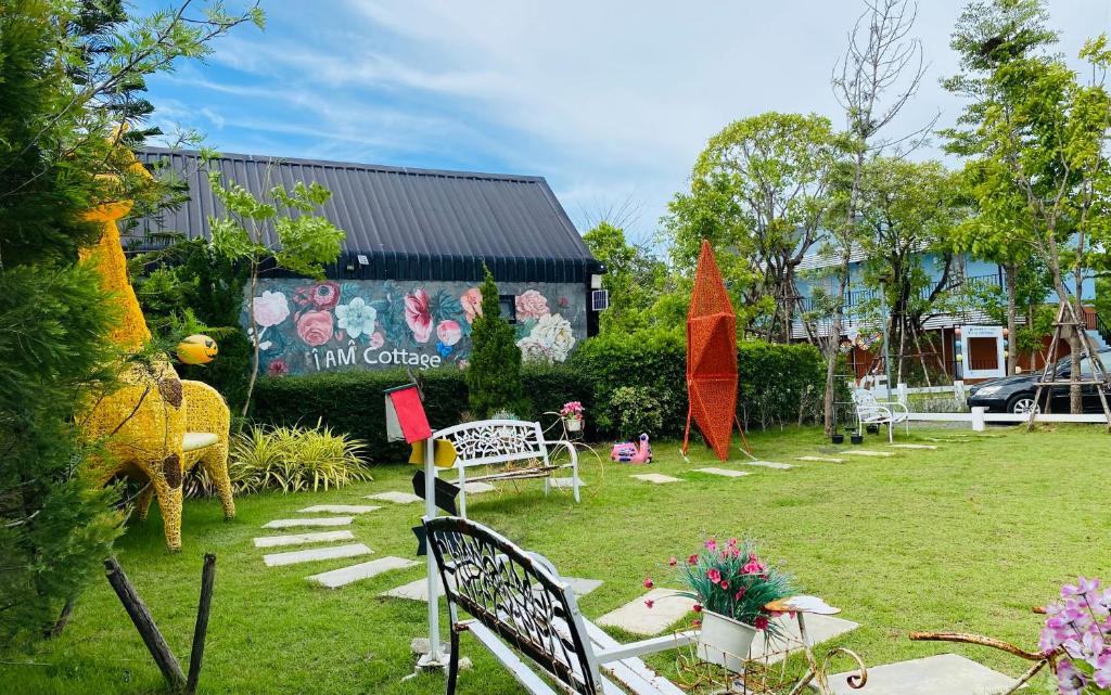 un jardín con bancos y mesas y un edificio en I AM Cottage เฮือนแก้วมณี, en Nakhon Pathom