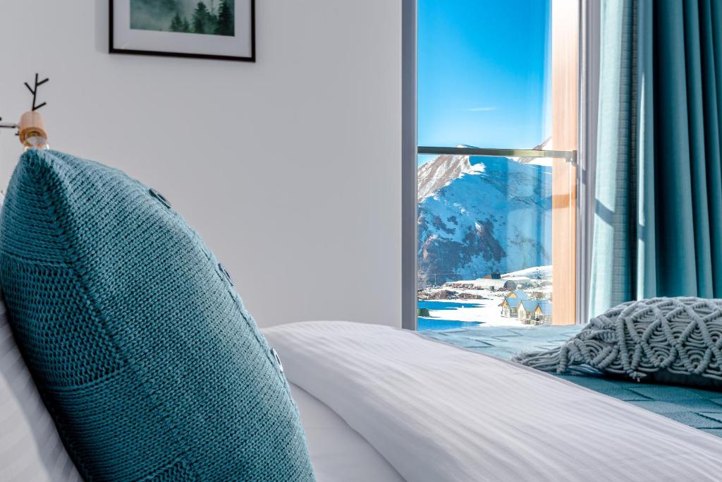a bedroom with a bed and a window with a view at New Gudauri GoodHost Apartments in Gudauri