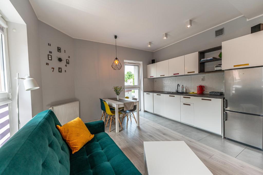 uma sala de estar com um sofá e uma cozinha em Emerald Apartament przy deptaku em Szczawno-Zdrój