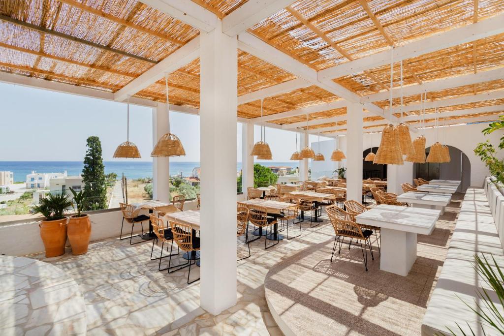 un restaurante con mesas y sillas y vistas al océano en Belmare Hotel-Adults Οnly, en Lardos