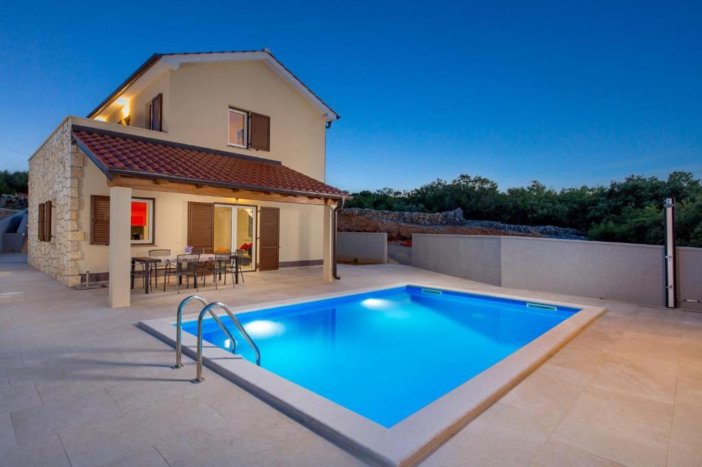 a swimming pool in front of a house at Villa Maestral in Vrbnik