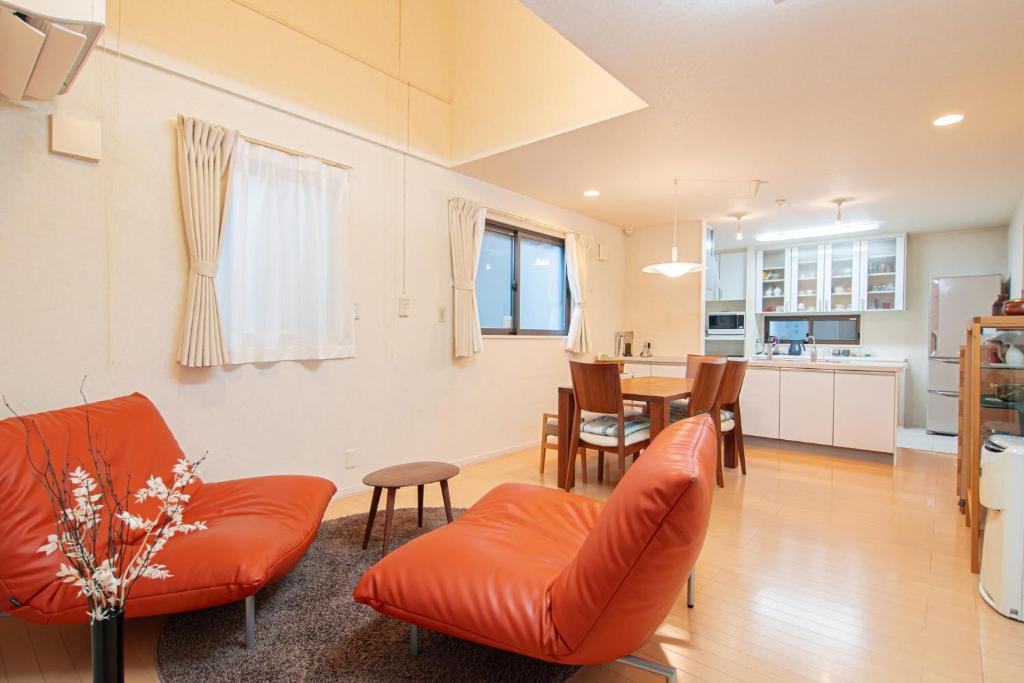 un soggiorno con divano arancione e tavolo di The Wisteria ad Osaka