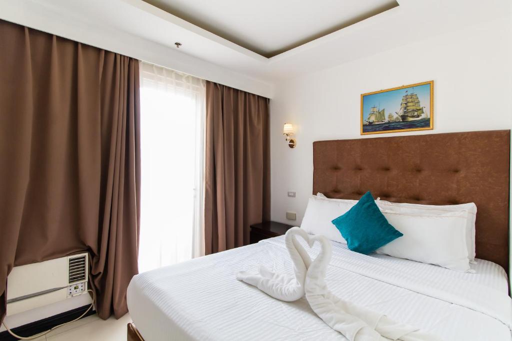 Pacific Bay Grand Suites في مانيلا: غرفه فندقيه بسرير ونافذه