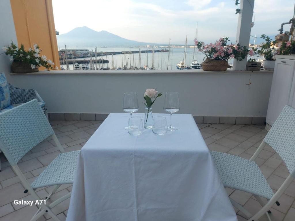 a table with glasses and flowers on a balcony at Coralinetiny in Castellammare di Stabia