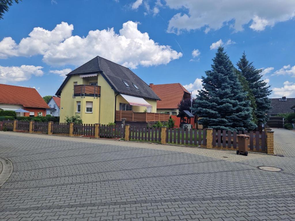 a yellow house with a fence and a tree at Ferienwohnung Gretel in Görlitz