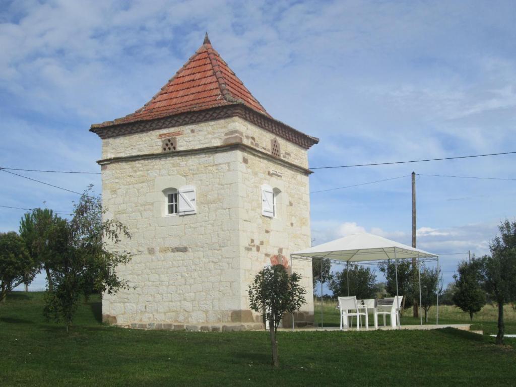 Un edificio con una torre con una mesa y una sombrilla. en Le pigeonnier, en Virac