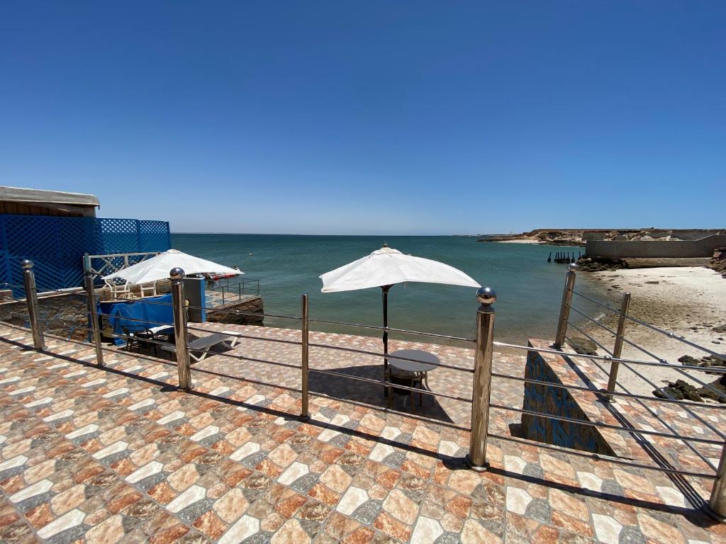 達赫拉的住宿－Hébergement dakhla plaisance，海滩上的两把遮阳伞和一张长凳