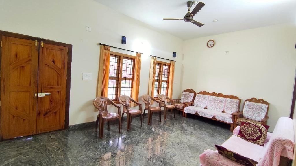 uma sala de espera com um monte de cadeiras e uma porta em Kurumbalakotta Village Homestay em Padinjarathara