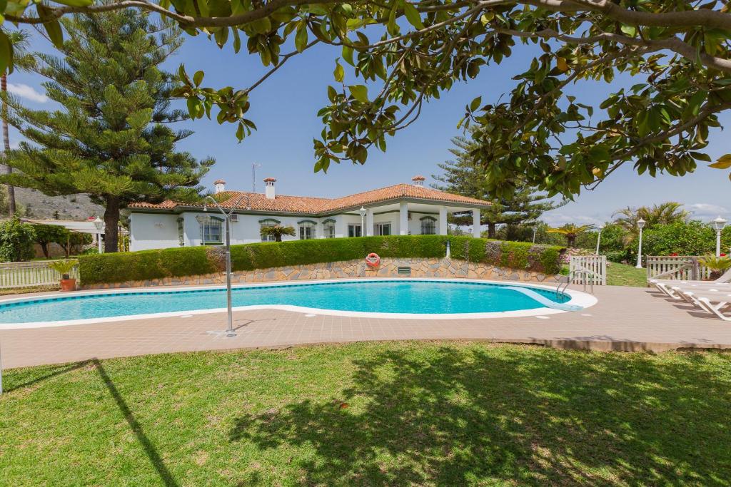 a swimming pool in front of a house at Villa Galemar Pool & Gardens in Torremolinos