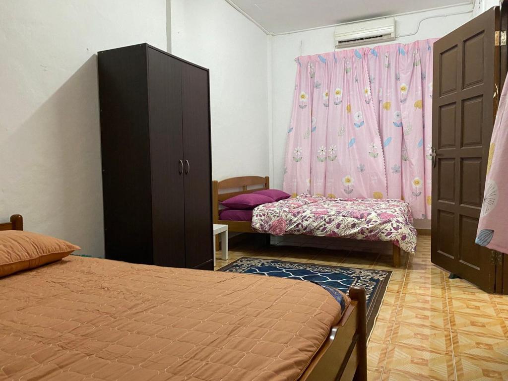 a bedroom with two beds and a pink curtain at Homestay Taman Maktab Pengkalan Chepa in Pengkalan Cepa
