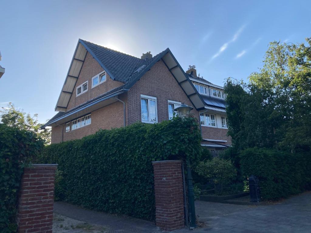 a large brick house with a hedge in front of it at 'Onder-dak' 2-persoons appartement in Zandvoort