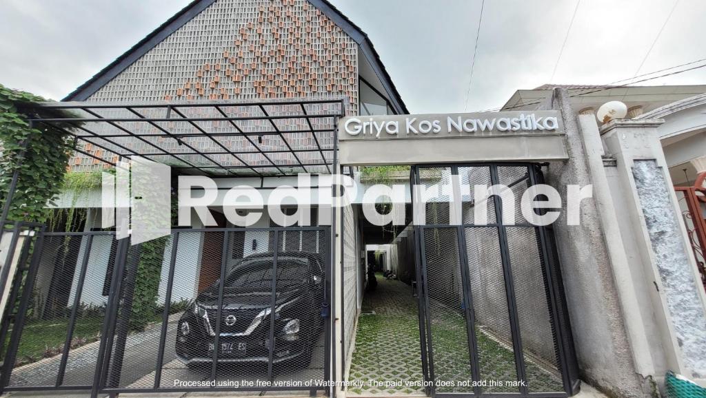 a gate with a car parked inside of a house at Griya Nawastika At Jakal KM 8 Mitra RedDoorz in Kejayan