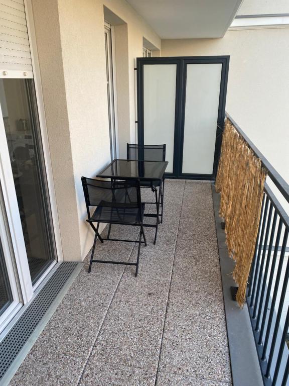 d'un balcon avec deux chaises et une table en verre. dans l'établissement BEAU STUDIO NEUF AVEC TERRASSE, au Blanc-Mesnil